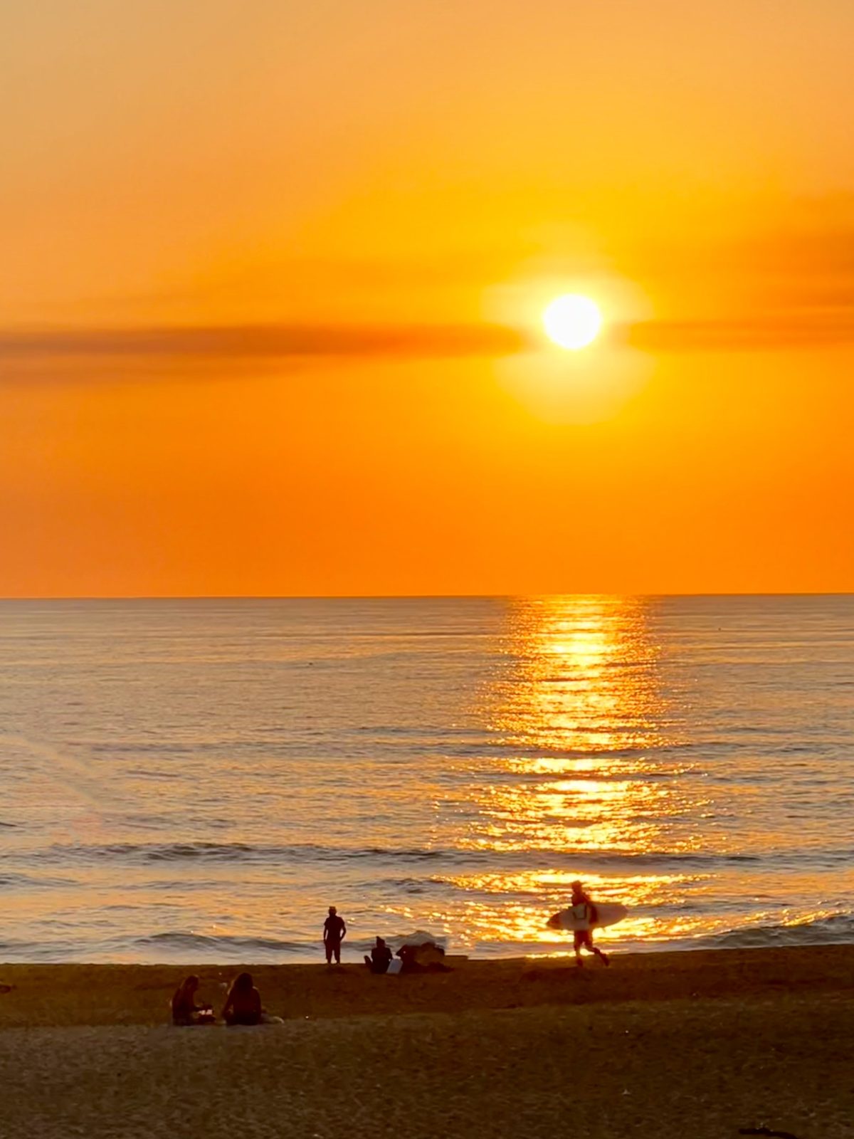Coucher de soleil sur l'ocean a Hossegor, un surfeur traverse la plage