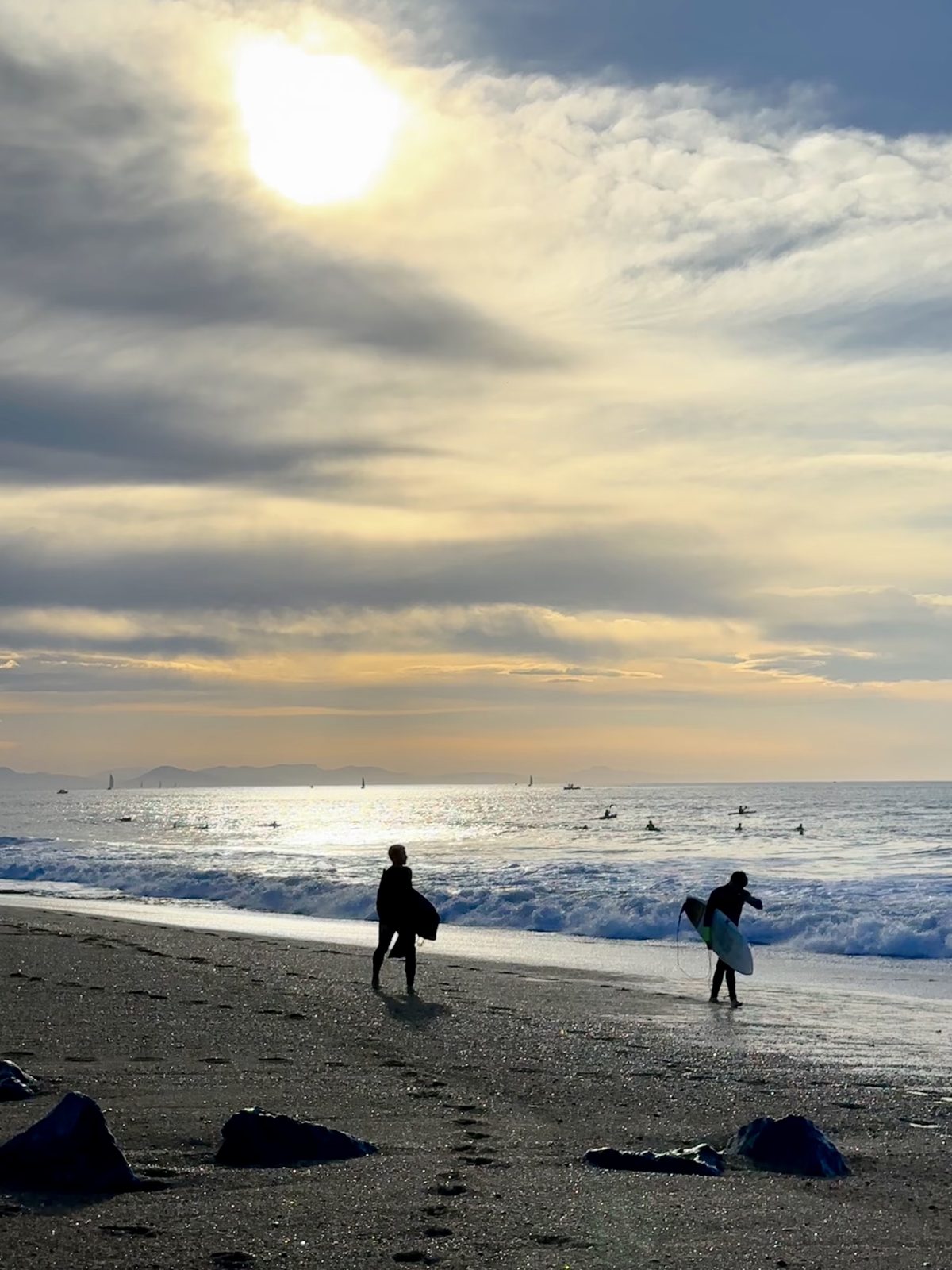 Deux surfeurs marchent sur la plage d'Hossegor au coucher du soleil